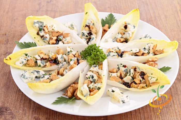 Witloof chicory leaves stuffed with blue cheese and walnuts on a white plate